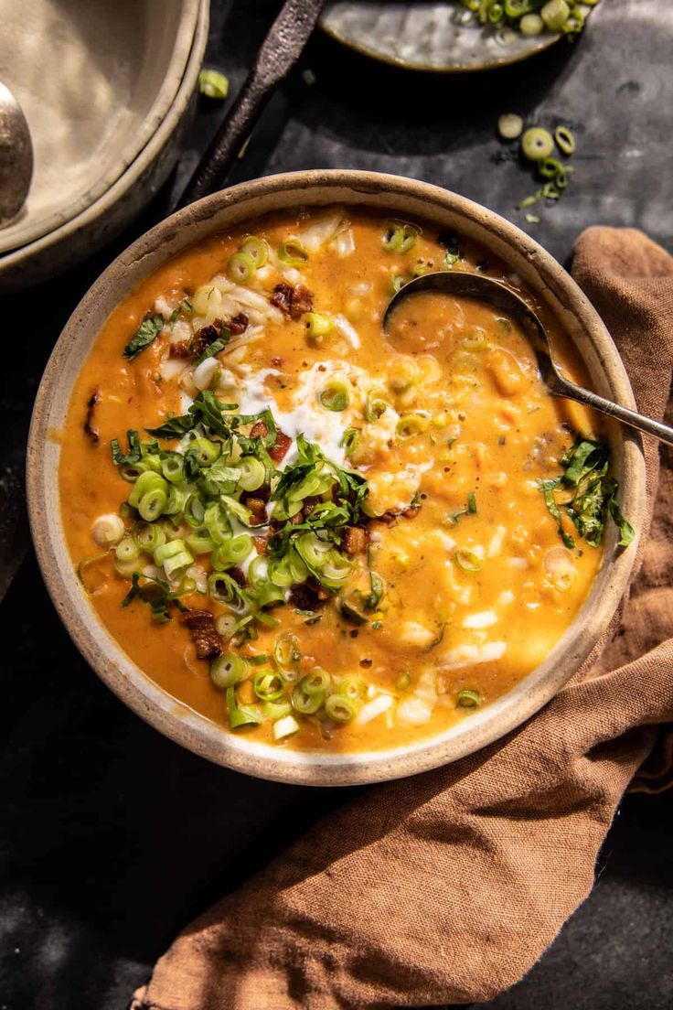 a bowl filled with soup and garnished with green onions, cheese and other toppings