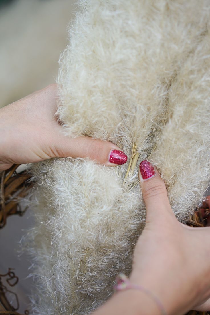 a woman with pink nail polish on her nails next to a fluffy white teddy bear