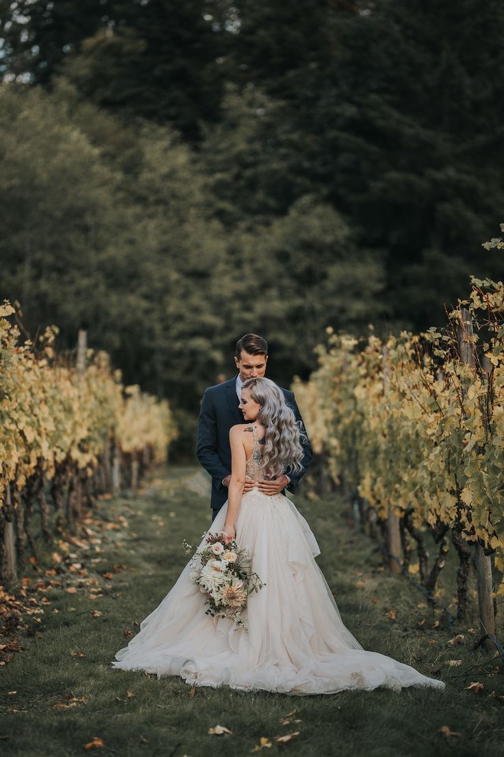 a bride and groom standing in the middle of a vineyard