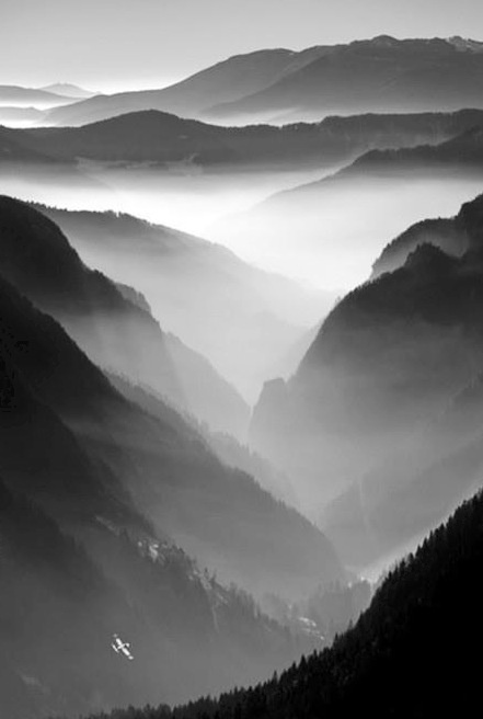 black and white photo of mountains with fog