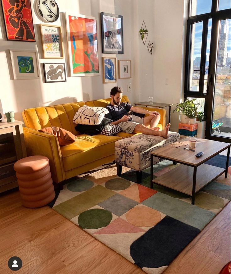 a man laying on top of a couch in a living room next to a window