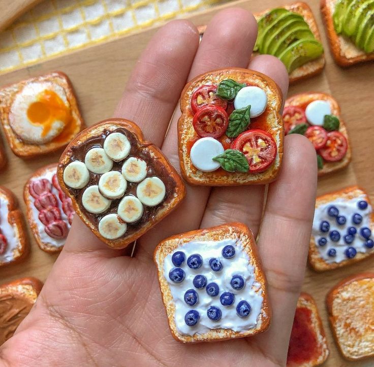 miniature sandwiches with fruit and vegetables on them are being held by someone's hand