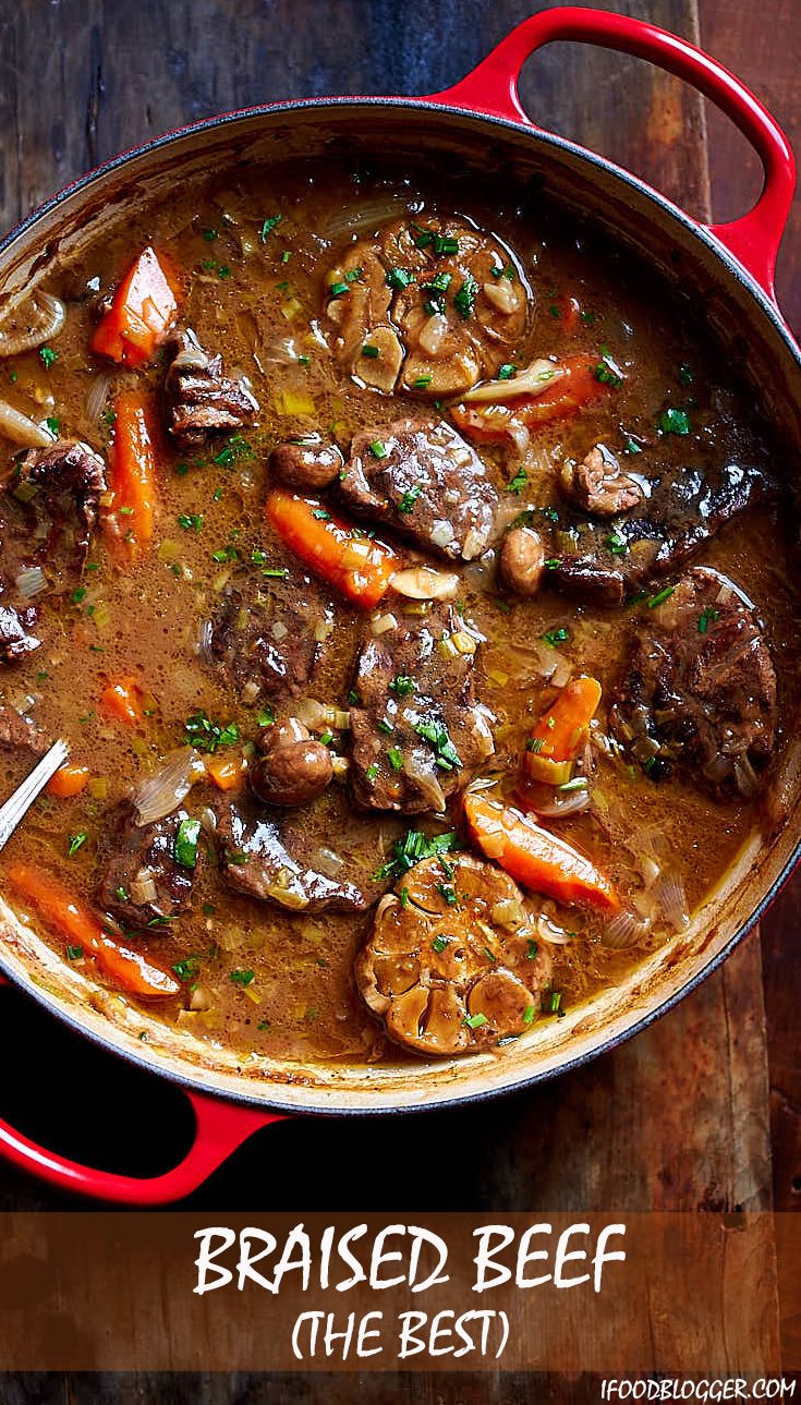 a red pot filled with stew on top of a wooden table