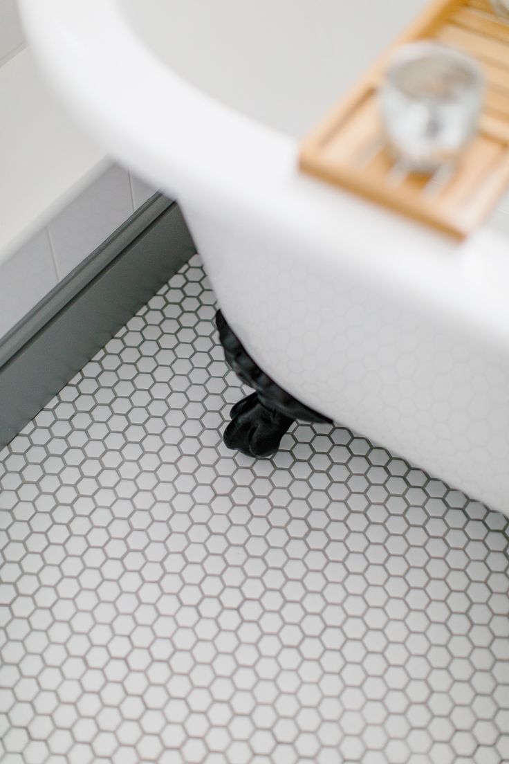 a white bath tub sitting on top of a bathroom floor next to a wooden tray