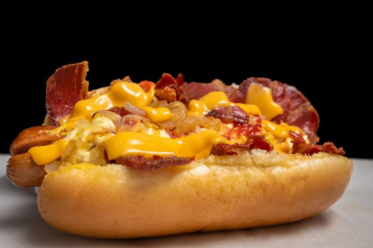 a hot dog covered in cheese and bacon