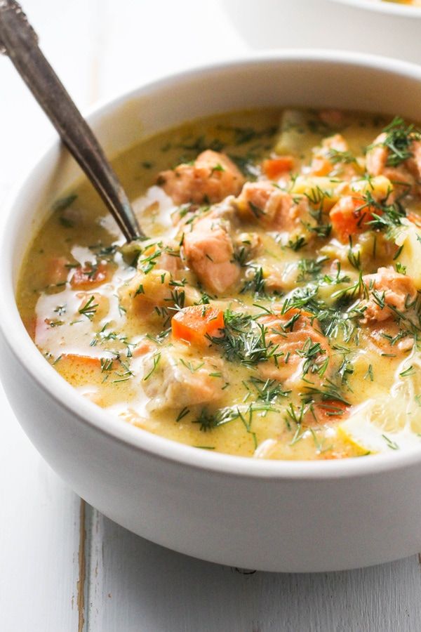 a white bowl filled with salmon and potato soup