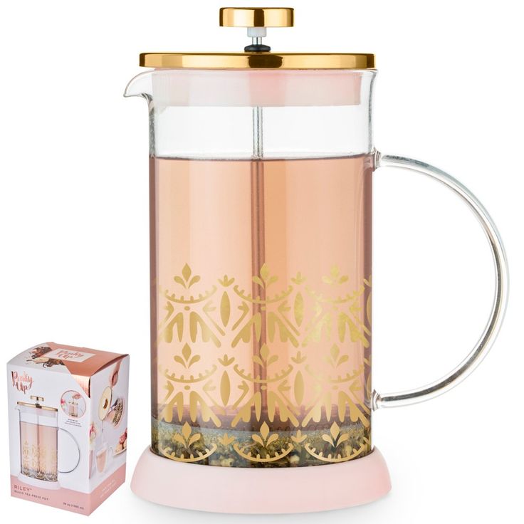 a glass tea pot filled with pink liquid and gold trimmings, on a white background