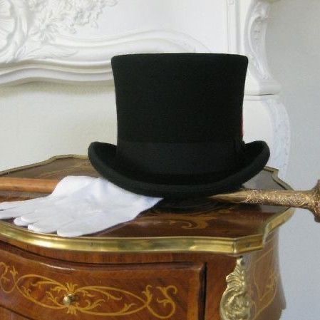 a black top hat sitting on top of a wooden dresser