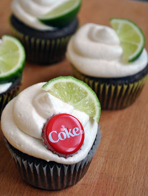 three cupcakes with lime and white frosting on top, one has a coke button