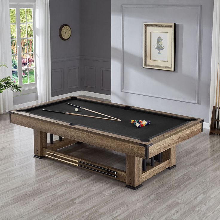 a pool table in the middle of a room with two cues and balls on it