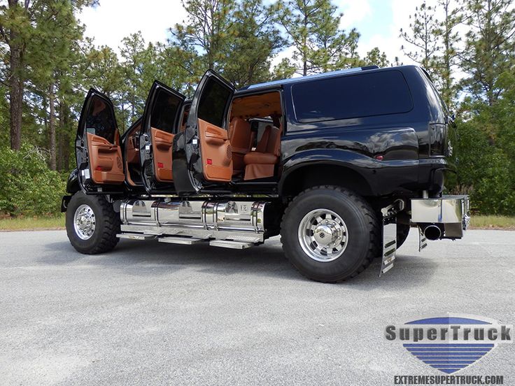 a black truck with tan leather seats is parked in a parking lot next to some trees