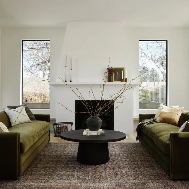 a living room with two couches and a table in front of the fire place