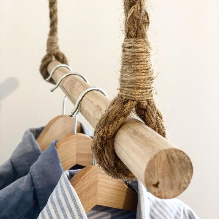 clothes hanging on wooden hangers with rope and wood pegs attached to the shirts