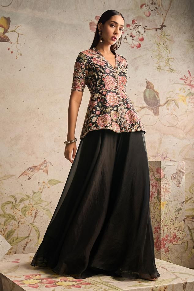 Black peplum top with floral print and zari thread, sequin, mirror embroidery. Paired with sharara. Components: 2 Pattern: Printed, Embroidery Type Of Work: Floral, zari thread, sequin, mirror Neckline: V neck Sleeve Type: Half sleeves Fabric: Peplum Top: Raw Silk, Sharara: Organza Color: Black Other Details:  Embroidered placket Occasion: Destination Wedding - Aza Fashions Printed Peplum Sharara Suit, Anniversary Party Guest Outfit, Elegant Traditional Outfits, Anniversary Guest Outfit, Silk Indo Western Outfits, Brocade Indo Western Outfits, Brocade Skirt And Top, Indian Sharara Outfits, Black Traditional Dress