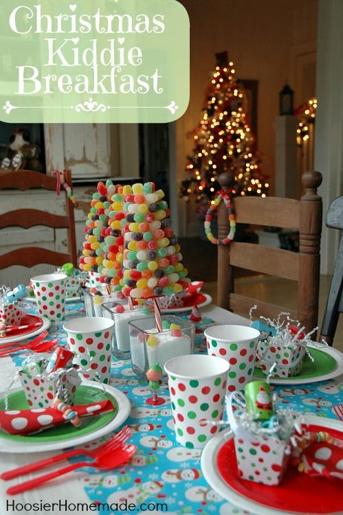 a table set for christmas with cups, plates and candy in front of the tree