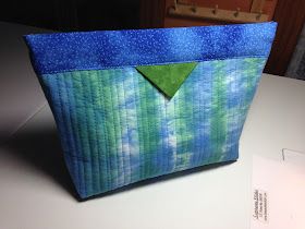 a blue and green bag sitting on top of a table next to a piece of paper