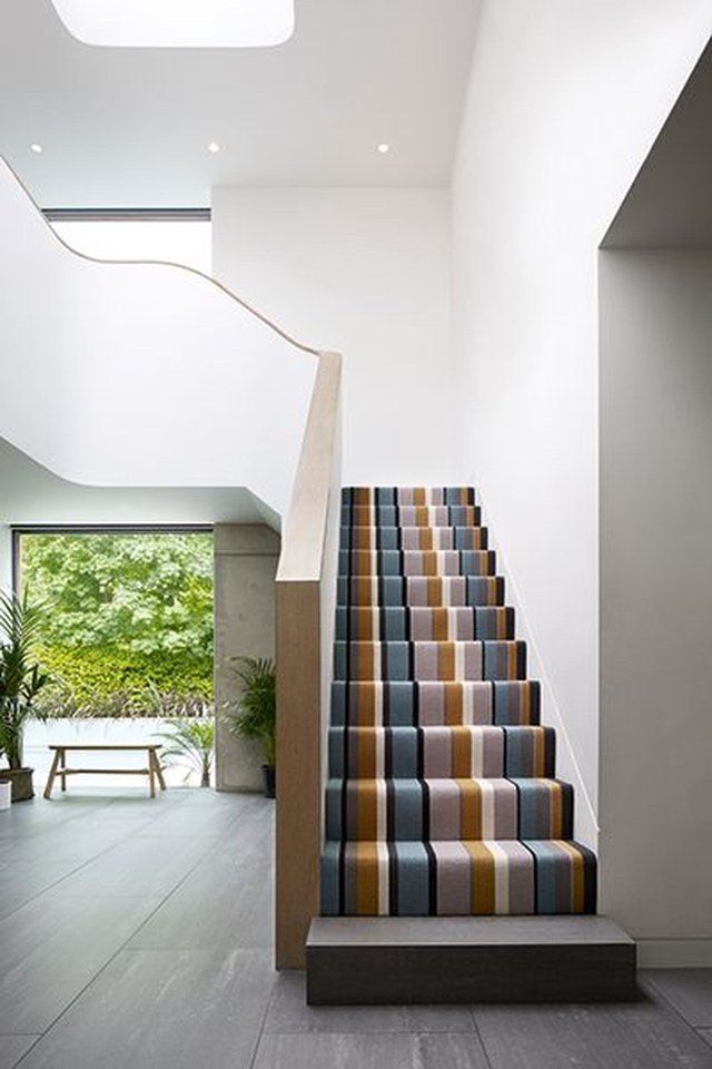 the stairs are lined with multicolored carpet in this modern house, which also has an open floor plan