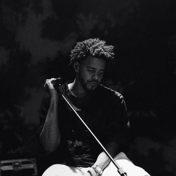 a black and white photo of a man sitting on the ground with a microphone in his hand