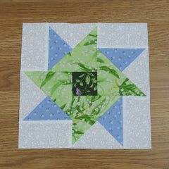 a green and blue star quilted on top of a wooden table