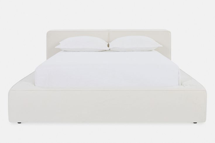 a white bed with two pillows on top of the headboard and one foot board