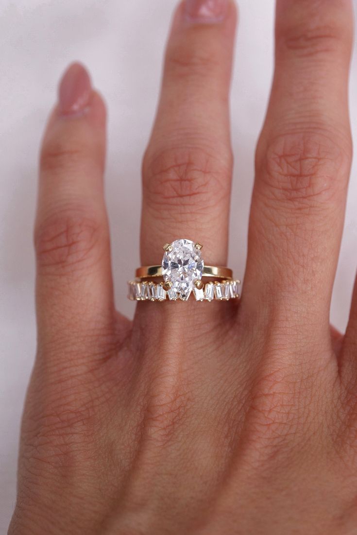 a woman's hand with a diamond ring on top of her finger and an engagement band