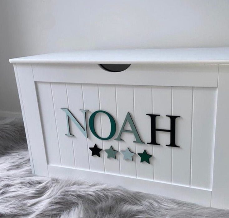 the name noah is written in green and black letters on a white wooden box with stars