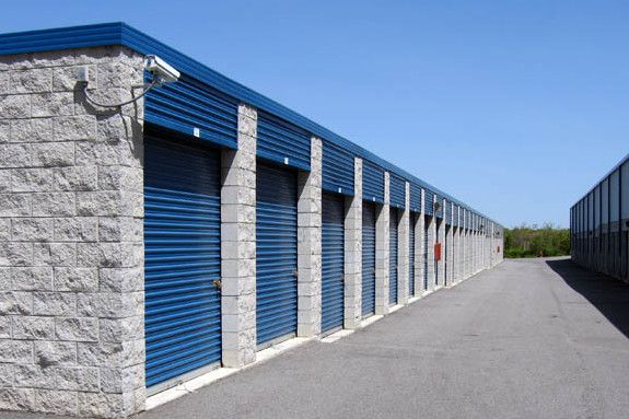 a row of storage units with blue doors on each side and one closed door in the middle