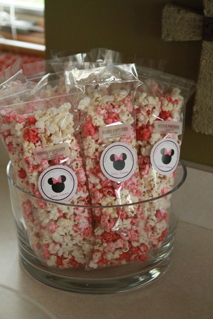 some kind of popcorn in a glass bowl on a table with minnie mouse stickers