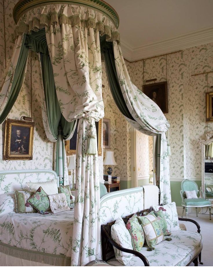 a canopy bed sitting in the middle of a bedroom next to a chair and table