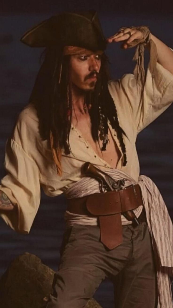 a man with dreadlocks wearing a pirate costume and holding his hat on his head