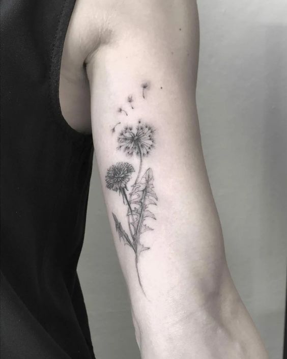 a woman's arm with a dandelion tattoo on it