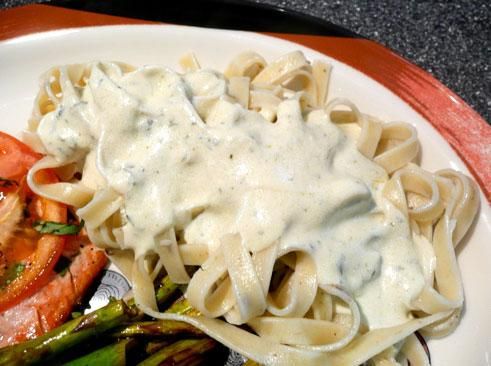 a white plate topped with pasta, asparagus and salmon