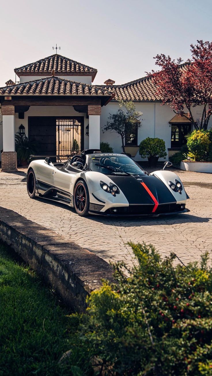 a black and white sports car parked in front of a house with red stripes on it