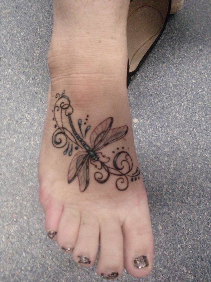 a woman's foot with a dragonfly tattoo on it