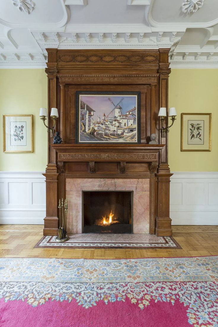 a living room with a fire place in the center and paintings on the wall above it