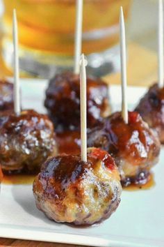 small meatballs with toothpicks on a white plate next to oranges and ketchup