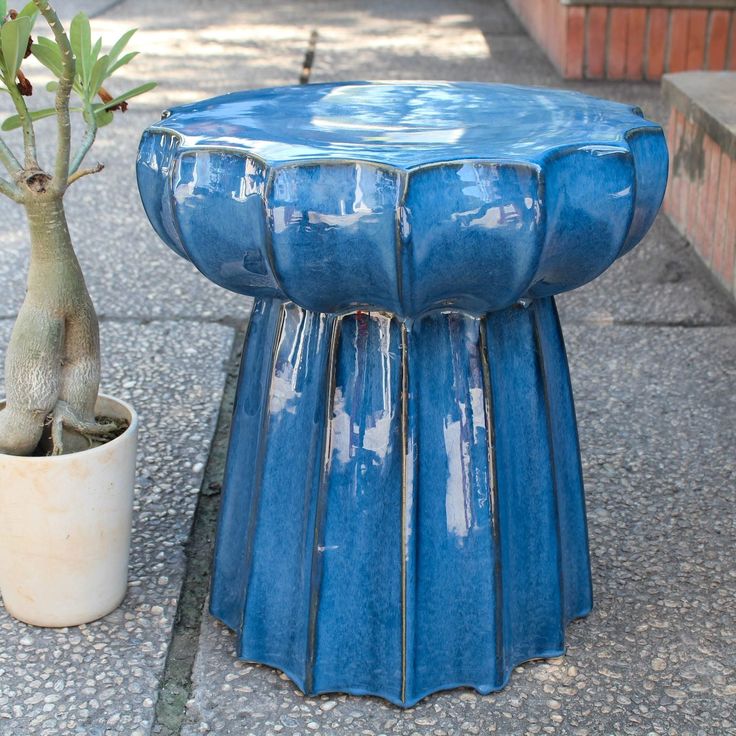 a blue stool sitting next to a potted plant