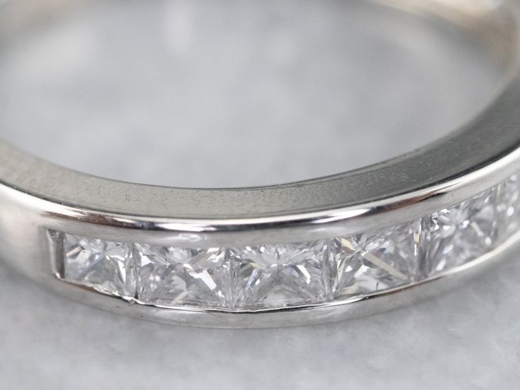 This sleek wedding band is set with a glittering row of square-cut, fine diamonds. The look they create is very 'Deco', and very modern at the same time, this is a great piece for a wedding day or stacking ring. Channel settings never go out of style! The effect of one long row of diamonds, one band of glittering bright light, across the finger is always popular and always lovely. The sides of the ring completely encase the diamonds, keeping them safe and secure, which makes these rings easy to Modern Diamond Half Eternity Band, Modern Half Eternity Diamond Band, Silver Radiant Cut Eternity Band For Formal Occasions, Modern Diamond Eternity Band For Anniversary, Formal Emerald Cut Half Eternity Stackable Rings, Modern Silver Eternity Band For Formal Occasions, Luxury Square Cut Channel Set Rings, Modern Emerald Cut Half Eternity Diamond Ring, Modern Cubic Zirconia Eternity Band For Anniversary