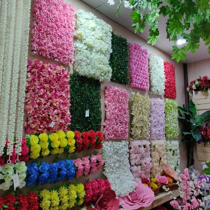 many different colored flowers are arranged on the wall in front of each other and hanging from the ceiling