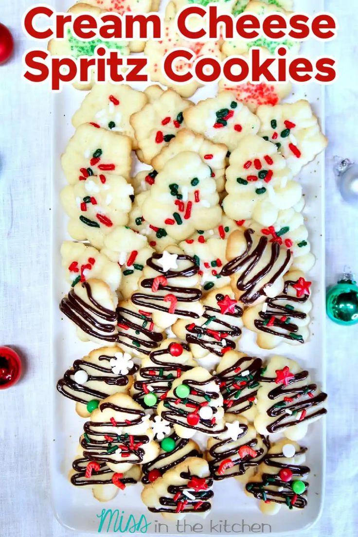 a white plate topped with cookies covered in frosting and sprinkles next to christmas decorations