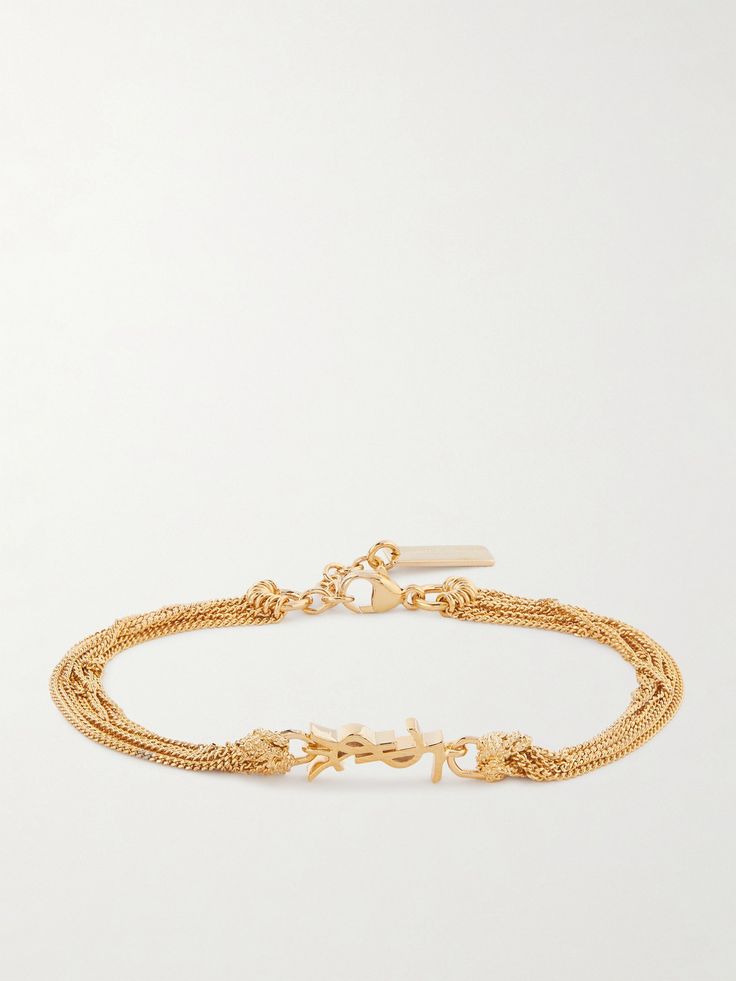 SAINT LAURENT's bracelet is centered with the iconic 'Cassandre' logo, which is flipped on its side. It's made from gold-tone metal and strung with layers of swishy chains that create the illusion of a stack. Wear yours with a sleeveless gown or allow it to peak out from the cuff of a collared shirt. Latest Bracelets, Wave Bracelet, Flat Dress Shoes, Floral Dresses Short, Sleeveless Gown, Fine Jewelry Designers, Pink Bracelet, Gold Tone Metal, Crystal Bracelets