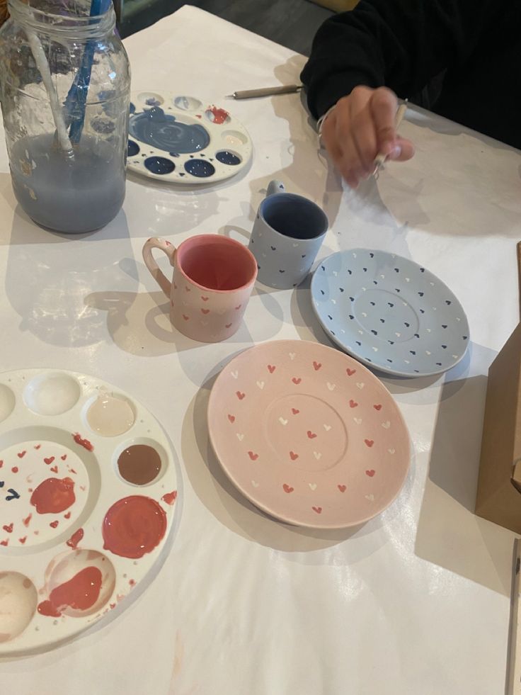 the table is set with plates, bowls and paintbrushes for painting on paper