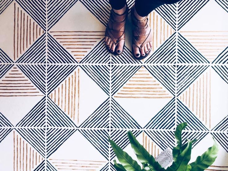 a person standing on top of a tiled floor next to a potted green plant