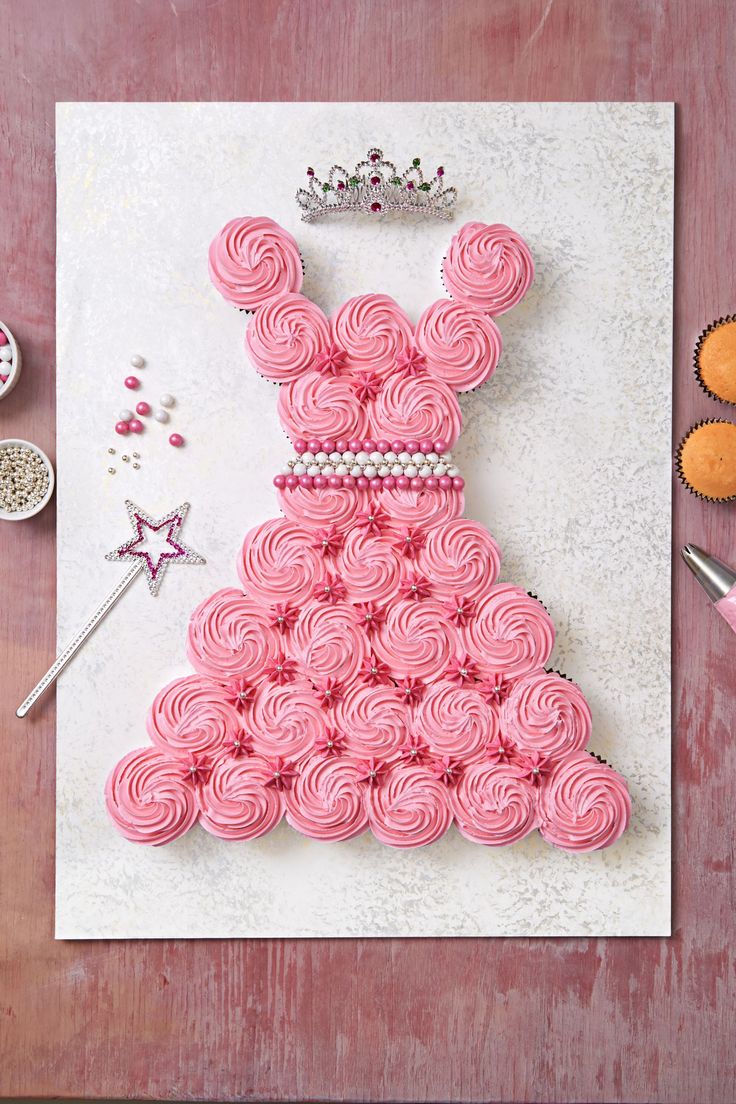 a pink dress made out of cupcakes on top of a white paper sheet