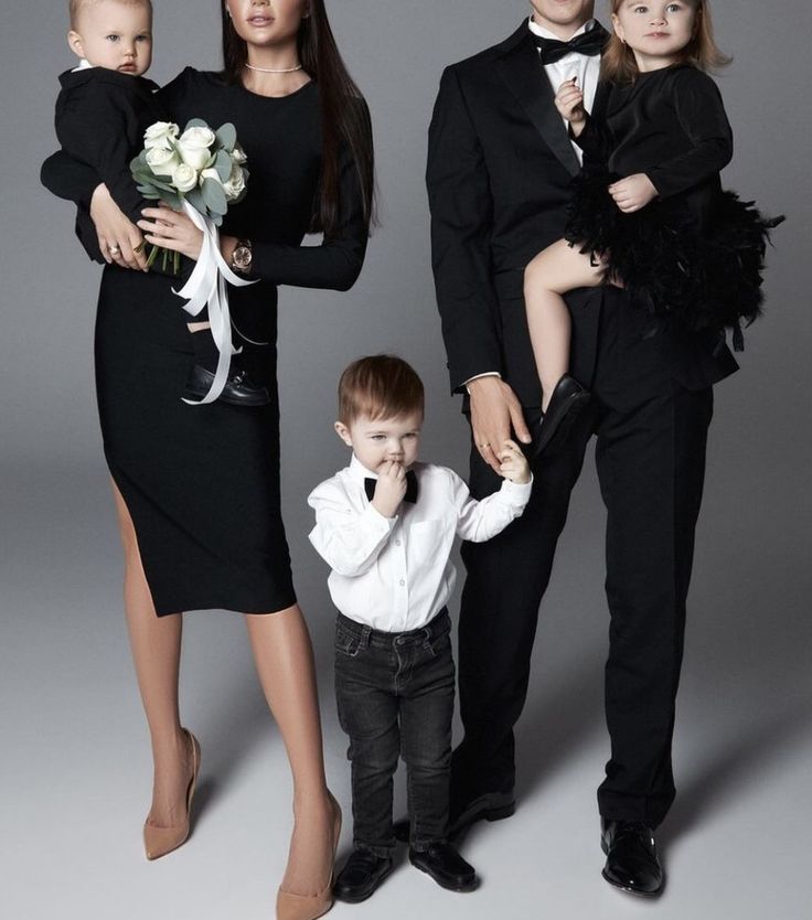 a family posing for a photo in formal wear and tuxedo, with the child holding his mother's hand