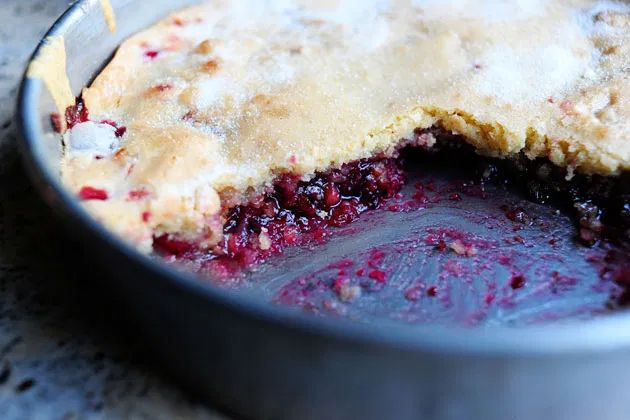 a pie crust in a pan filled with blueberry cobbler filling and crumbs