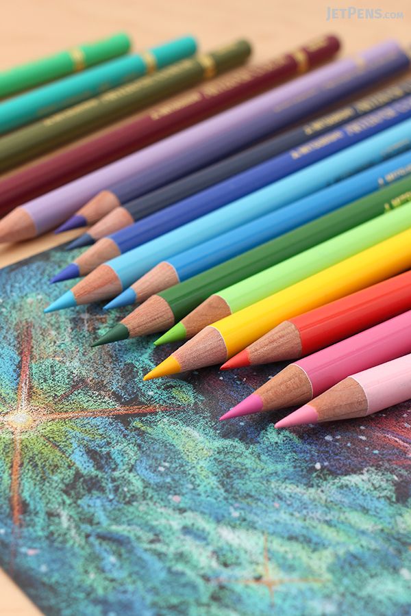 several colored pencils lined up on top of a drawing book with stars in the background