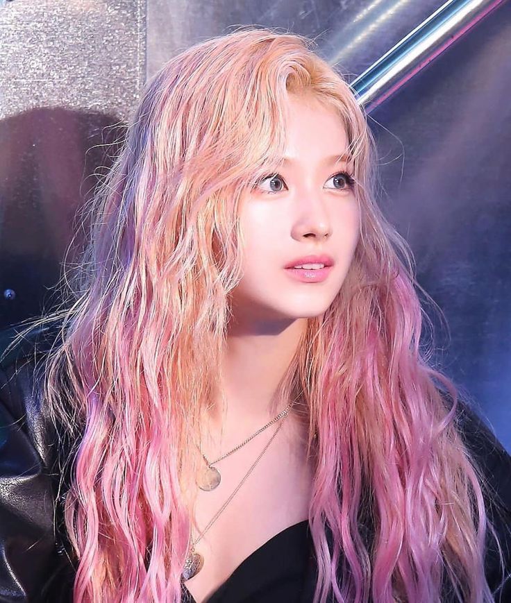 a woman with long pink hair wearing a black top and leather jacket looking at the camera