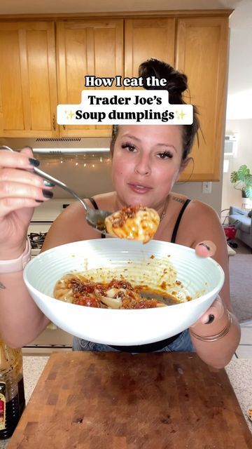 a woman holding a bowl of food with the words how i eat the trader joe's soup dumplings