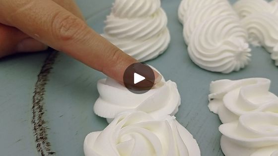 someone is pointing at some white icing roses